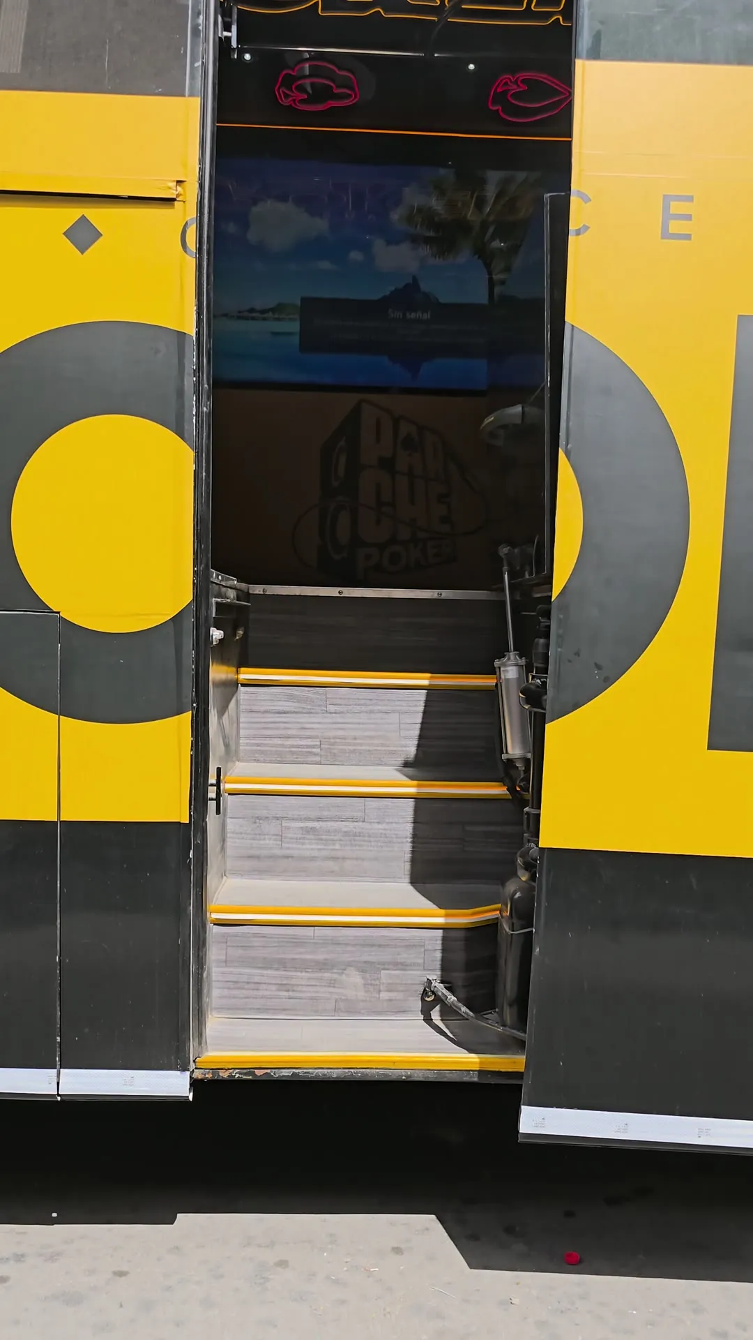 Puerta del bus de Cerveza Poker abierta, con el wrap amarillo y negro de la marca