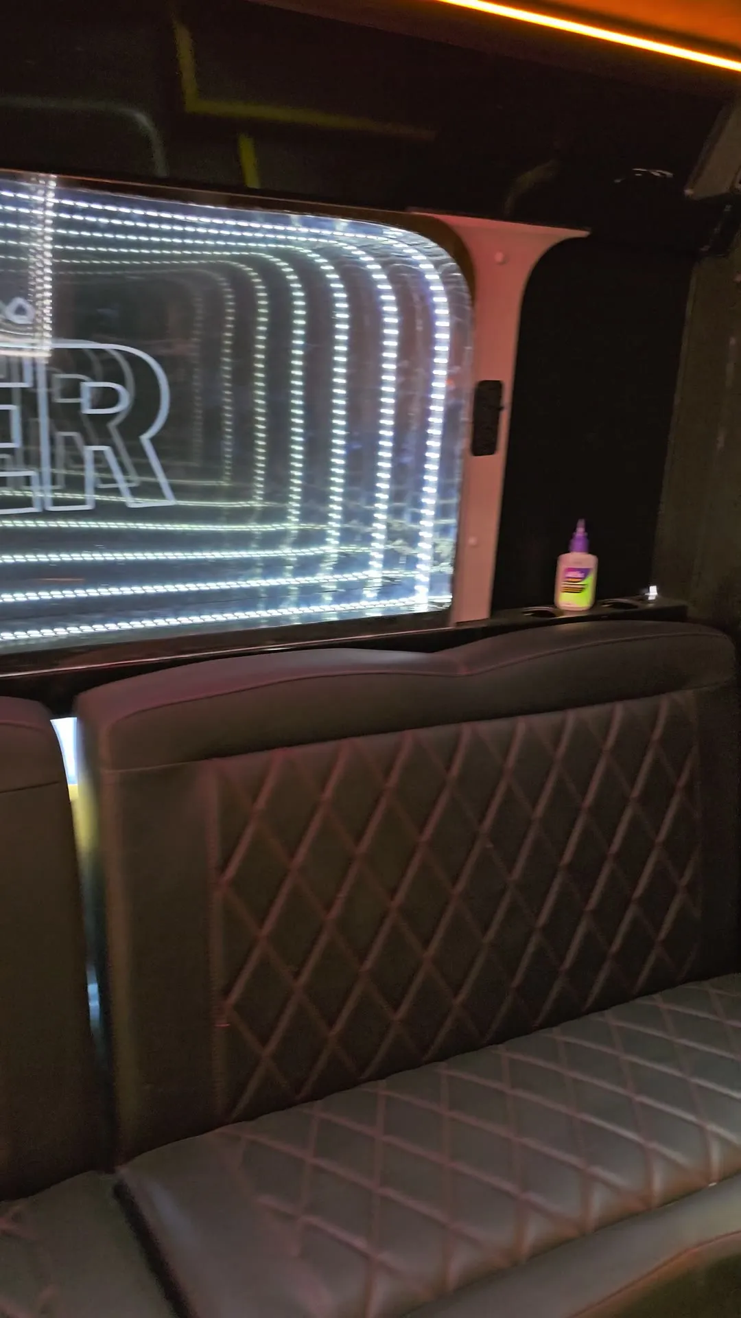Panel de espejo infinito con el logo de Poker sobre los sofás del bus