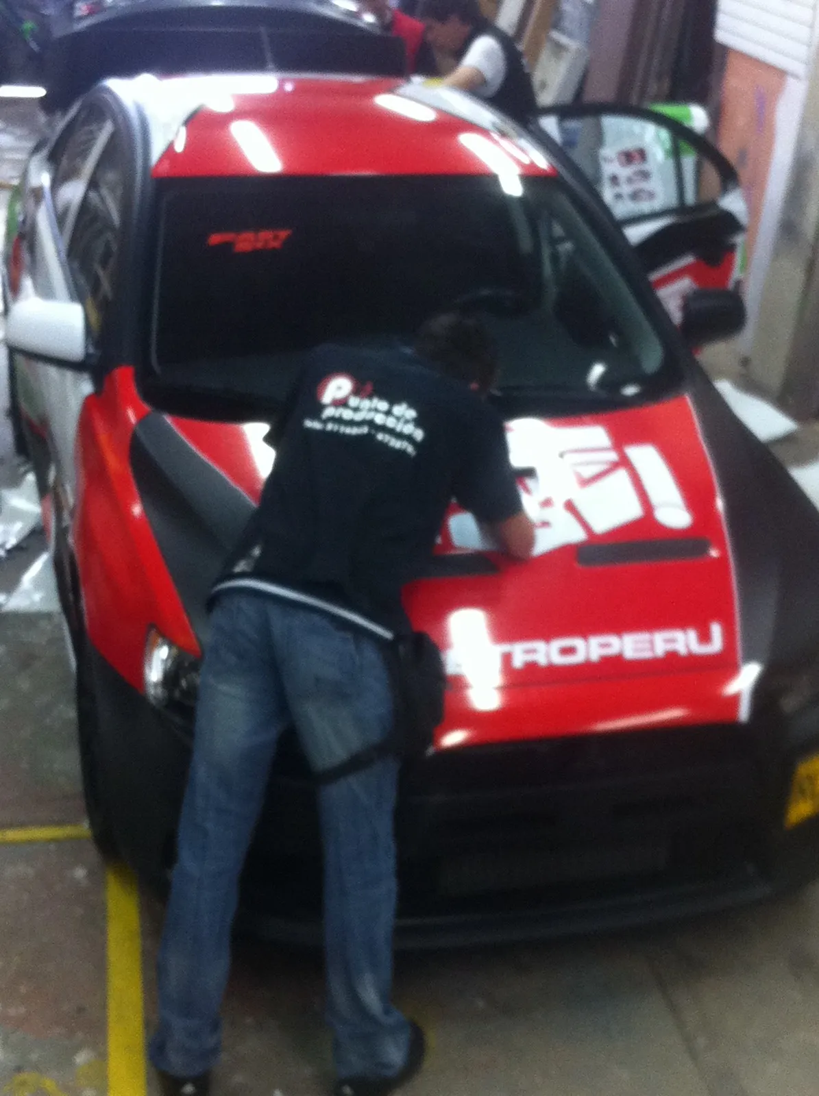 Instalador de En Punto aplicando vinilo sobre el capó del carro